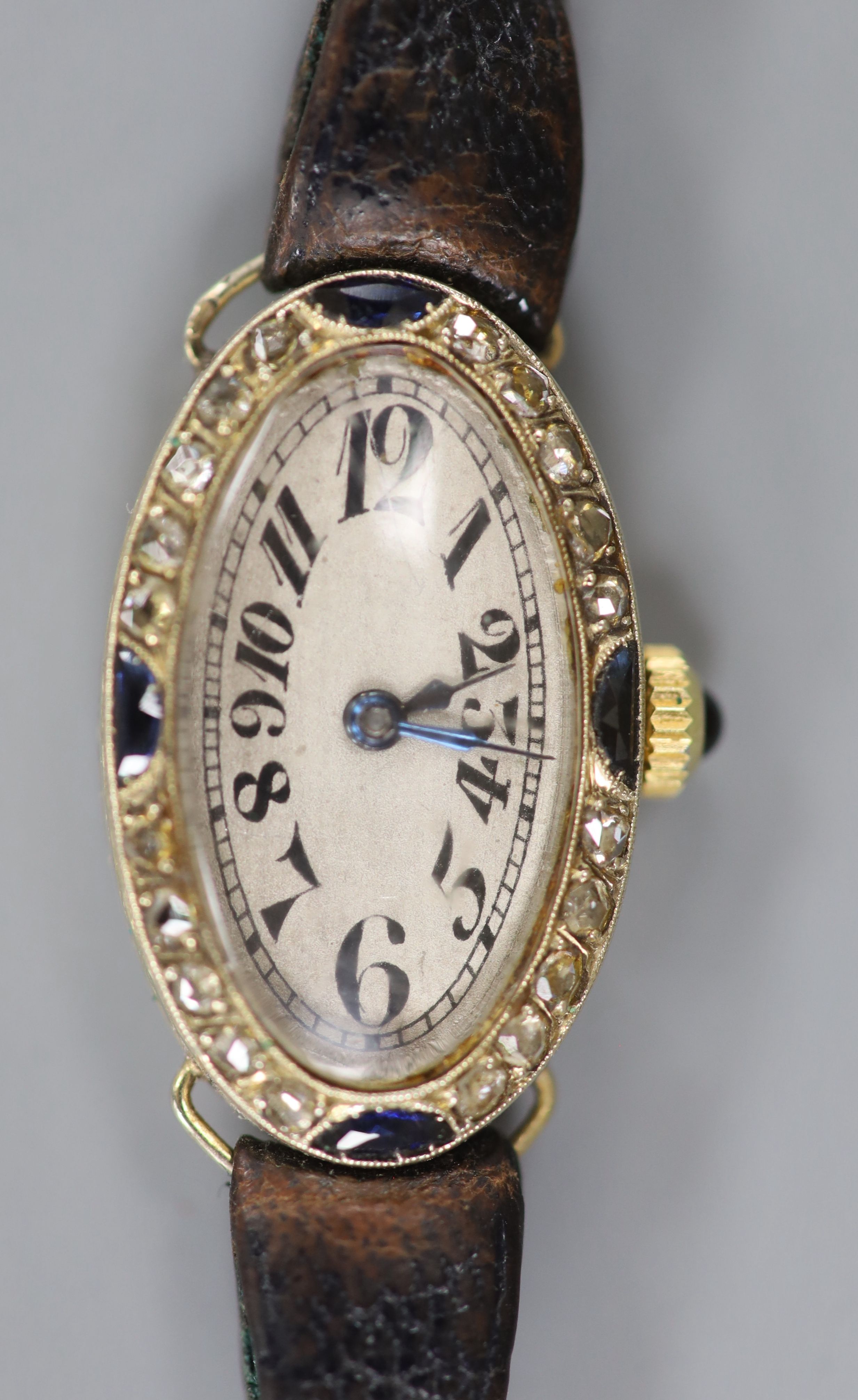 A lady's 1930's/1940's French yellow metal (18ct poincon mark), rose cut diamond and synthetic? sapphire set oval cocktail watch, with tumbling numerals, on a leather strap.